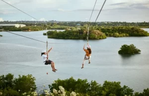 Dos personas volando en tirolina doble sobre un embalse rodeado de naturaleza en el Valle de Tena.