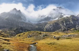 Paisaje del Valle de Tena con montañas nevadas, nubes bajas y pradera, ideal para disfrutar del columpio panorámico de Hoz de Jaca en los Pirineos aragoneses.