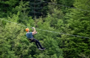 Deportes de aventura para liberar estrés: persona deslizándose en tirolina con montañas del Valle de Tena al fondo